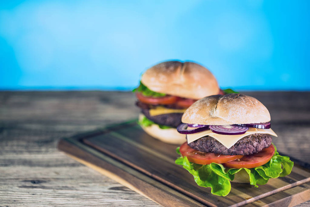 dos hamburguesas de queso sabrosas frescas en tablero de madera, concepto de comida rápida
  - Foto, imagen