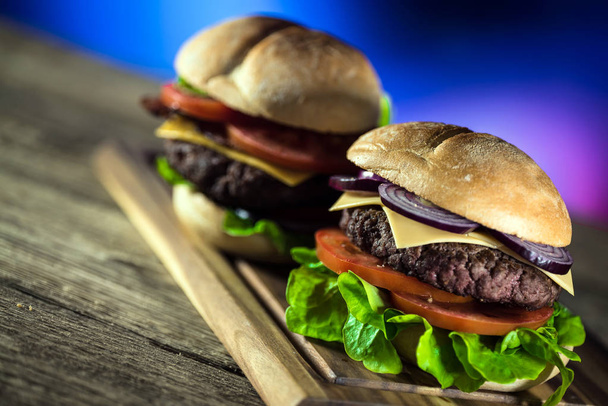 két friss ízletes sajtburgert, fából készült táblán, gyorsétterem koncepció  - Fotó, kép