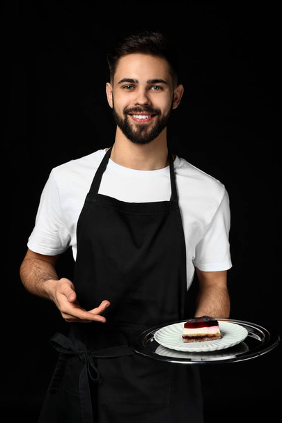 Przystojny kelner z deser na ciemnym tle - Zdjęcie, obraz