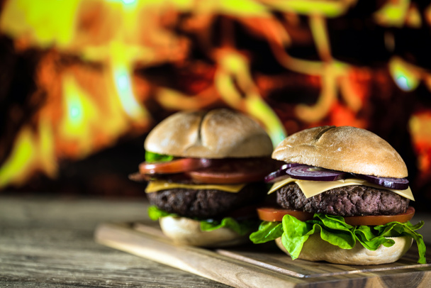 two fresh tasty cheeseburgers on wooden board, fast food concept  - Photo, Image