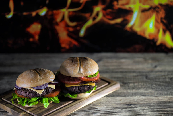 dois cheeseburgers saborosos frescos na placa de madeira, conceito do fast food
  - Foto, Imagem