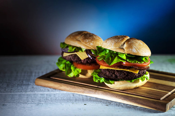 dos hamburguesas de queso sabrosas frescas en tablero de madera, concepto de comida rápida
  - Foto, imagen