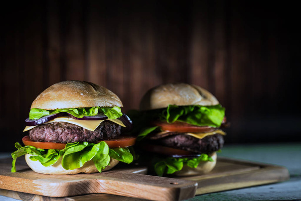 two fresh tasty cheeseburgers on wooden board, fast food concept  - Photo, Image