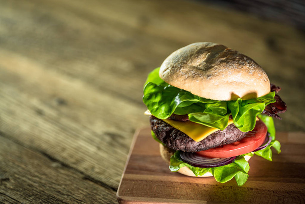 fresh tasty cheeseburger on wooden board, fast food concept  - Фото, изображение