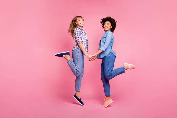 Volledige lengte lichaam grootte weergave van twee persoon mooi uitziende aantrekkelijke mooie charmante vrolijke vrolijke meisjes plezier hand in hand geïsoleerd over roze pastel achtergrond - Foto, afbeelding