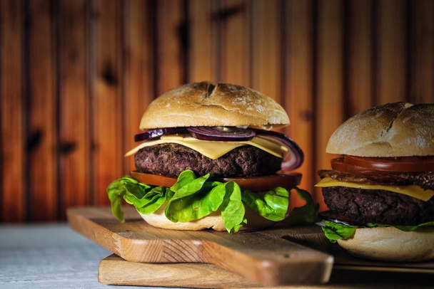 twee verse smakelijke cheeseburgers op houten bord, fast-food concept  - Foto, afbeelding