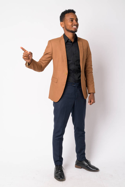 Cuerpo entero de joven empresario africano feliz pensando y señalando con el dedo
 - Foto, imagen