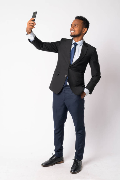 Plan complet du corps de heureux jeune homme d'affaires africain beau prenant selfie
 - Photo, image