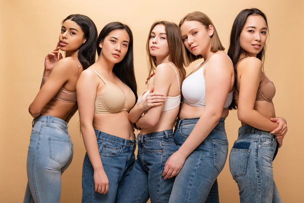 пять красивых мультикультурных девушек, позирующих перед камерой, изолированных от бежевого цвета, концепция позитивности тела
 - Фото, изображение