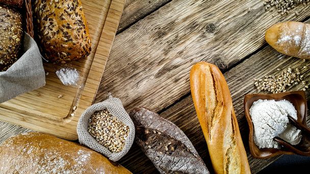 variety of delicious loaves of bread on wooden background  - Foto, Imagen