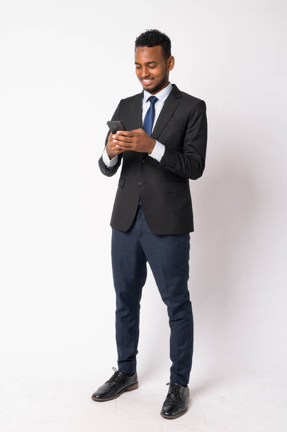 Cuerpo completo de joven feliz guapo empresario africano usando el teléfono
 - Foto, Imagen