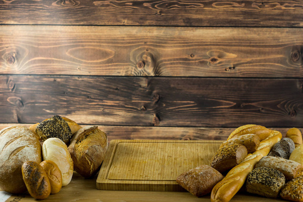 variety of delicious loaves of bread on wooden background  - Foto, Imagen