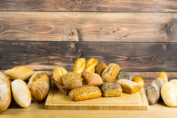 variety of delicious loaves of bread on wooden background  - Foto, Imagem