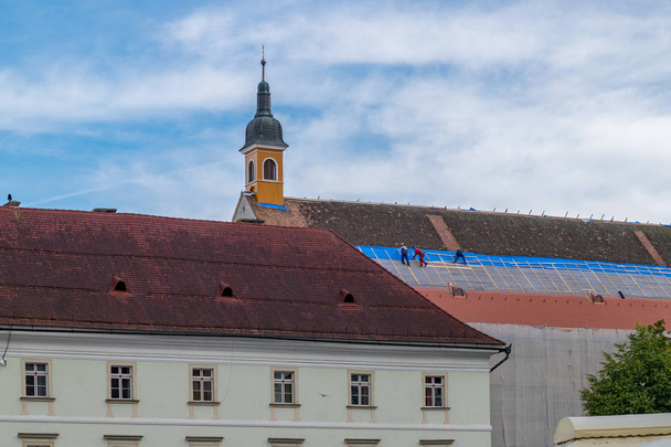 SIBIU, ROMANIA - 21 de julio de 2018: Trabajadores cambiando tejas de una antigua iglesia medieval en Sibiu, Rumania
 - Foto, imagen
