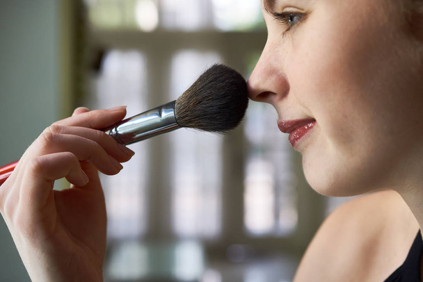 Close-up of young woman applying dry cosmetic foundation on her face using makeup brush - Photo, Image
