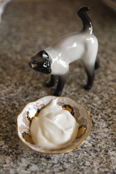 Kithcen テーブルと猫の陶像にサワー クリームとパンケーキ - 写真・画像