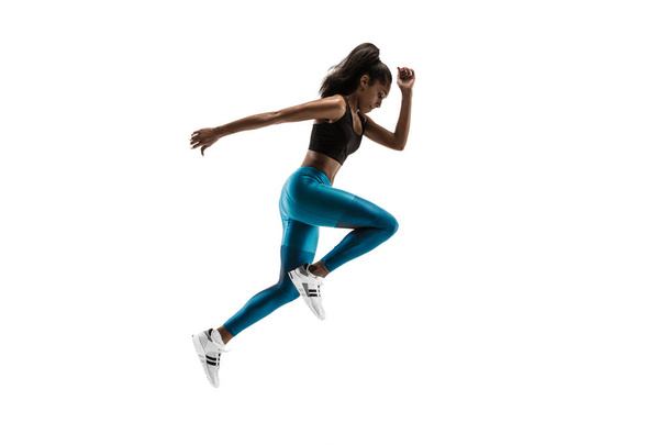 Young african woman running or jogging isolated on white studio background. - 写真・画像