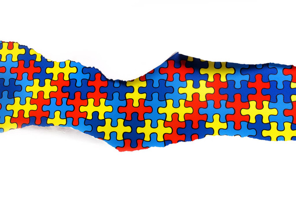torn white paper on multicolored puzzle background. Cocept for autism awareness day. Break barriers together for autism. - Fotoğraf, Görsel