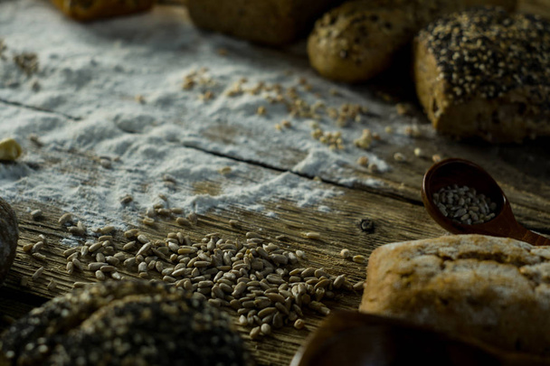 variety of delicious loaves of bread on wooden table with flour - Fotografie, Obrázek