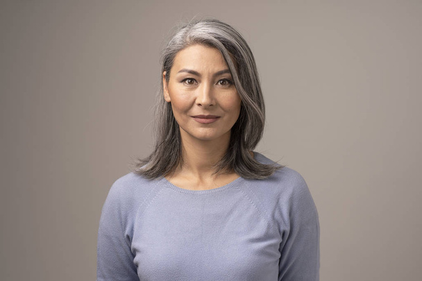 Beautiful Mongolian Woman with Gray Hair on a Gray Background. - Foto, afbeelding