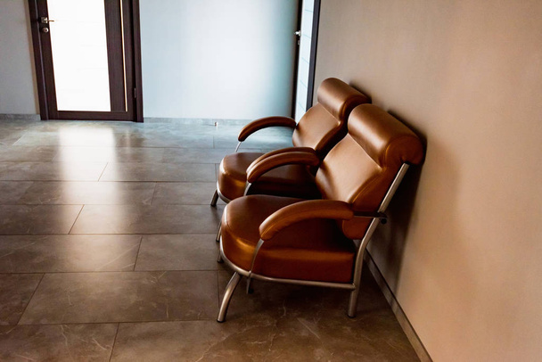 Duas cadeiras de couro marrom no salão ou na área de espera
 - Foto, Imagem