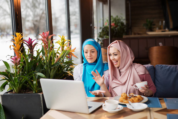 Μουσουλμάνες γυναίκες εργάζονται στο café και να χρησιμοποιούν τον υπολογιστή - Φωτογραφία, εικόνα