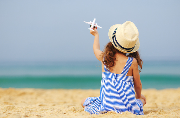 gyermek lány játék modell repülőgép a tengeren, a strandon    - Fotó, kép