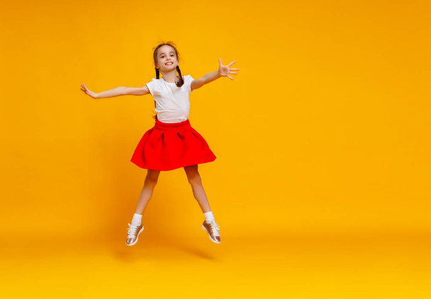funny child girl jumping on colored yellow backgroun - Photo, image