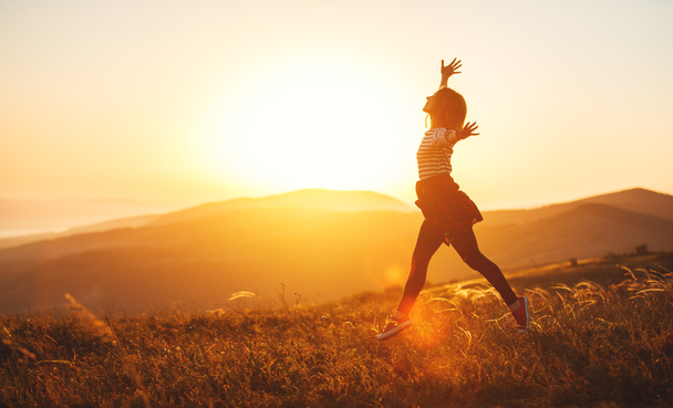 Mulher feliz pulando e aproveitando a vida ao pôr do sol na montanha
 - Foto, Imagem