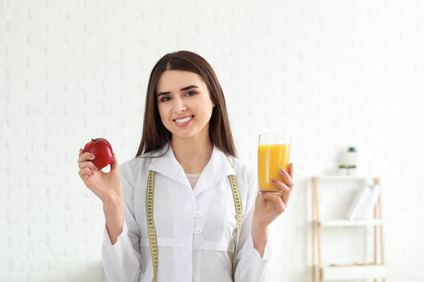 Портрет дієтолога з яблуком і склянкою соку в її офісі
 - Фото, зображення