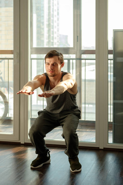 Un hombre guapo haciendo ejercicios de tablón contra la ventana de una casa
 - Foto, Imagen