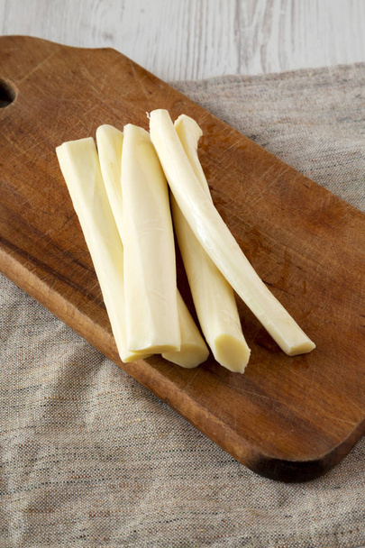String τυρί σε ρουστίκ ξύλινη σανίδα, πλευρική θέα. Υγιεινό σνακ.  - Φωτογραφία, εικόνα