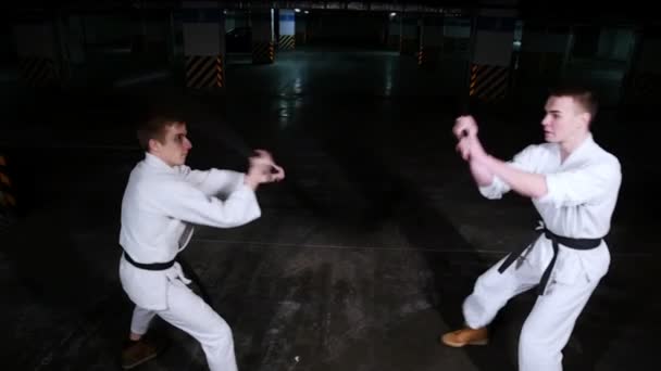 駐車場で自分のスキルを訓練する着物姿の二人の若者。剣の戦い - 映像、動画