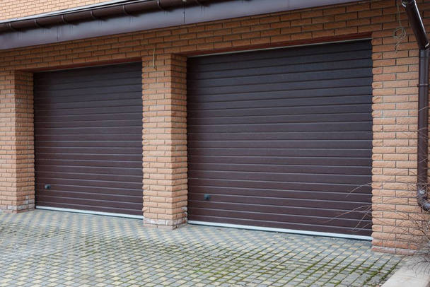 fachada de ladrillo garaje con dos puertas marrones en la calle
 - Foto, Imagen