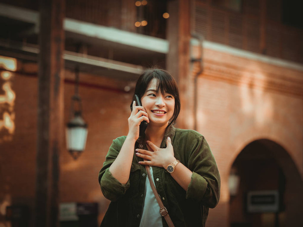 Mulher asiática usando smartphone com humor feliz no shopping
 - Foto, Imagem