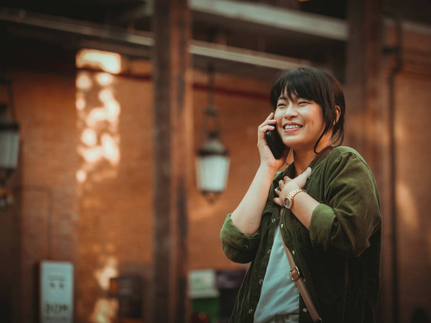 Donna asiatica utilizzando smartphone con umore felice nel centro commerciale
 - Foto, immagini