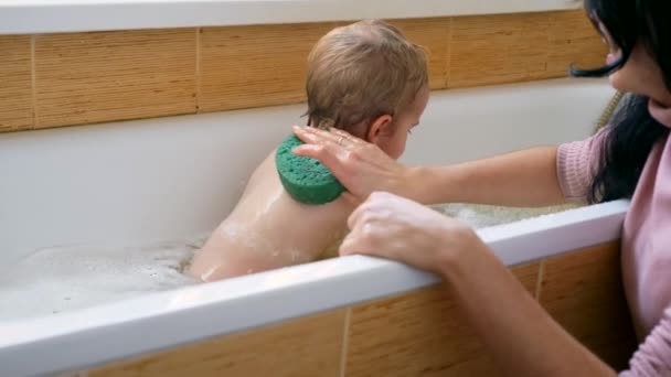 Mother Washes Her Child With Sponge Washcloth In Bathroom. Happy Joyful Child Bathes In Bath In Bathtub. Slow motion 0.5 speed 60 fps - Video