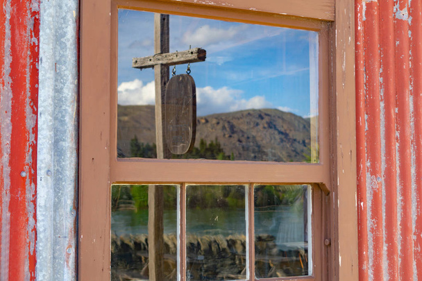 Lake Dunstan and hills around Cromwell reflected on old window g - Photo, Image