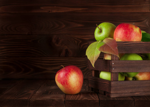 Manzanas en una caja rústica de madera sobre una vieja mesa rústica de madera. Manzanas rojas, verdes. Deliciosa manzana. Manzanas en la mesa
. - Foto, imagen