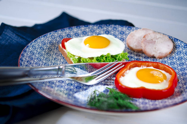 Sanduíche com ovo, presunto, queijo, torradas e folhas de salada fica em um prato com tomate e endro.
 - Foto, Imagem
