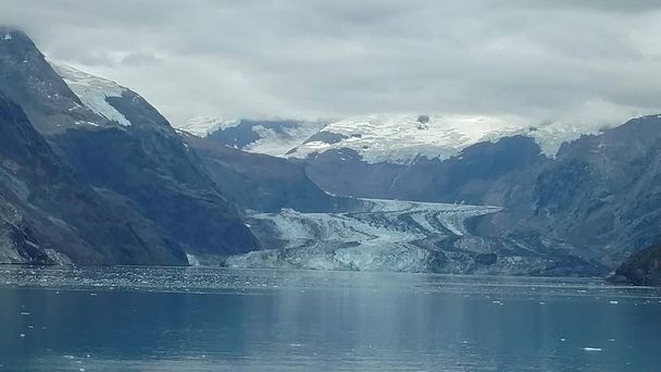 Glaciers within Glacier Bay National Park in Alaska. Glaciers coming over mountain peaks and sliding into the Pacific Ocean - Photo, Image