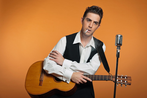 Retro country singer with guitar wearing black suit. Smoking cig - Φωτογραφία, εικόνα