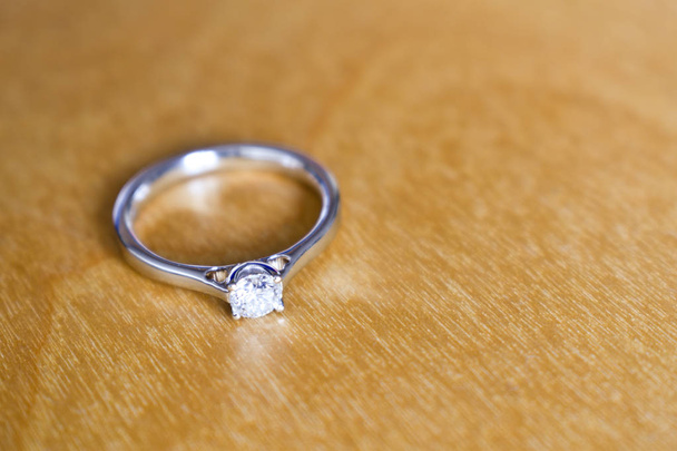 Diamant wit gouden verlovingsring op houten tafel - Foto, afbeelding