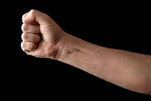 Fist isolated on black background. A strong man raised his fist on a black background, power, protest, fist ready for battle. - Фото, зображення
