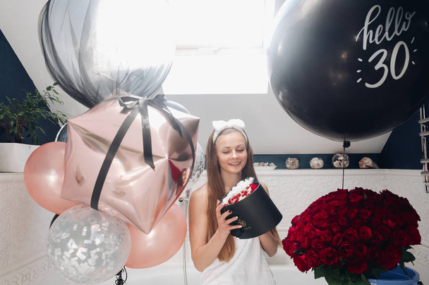 glückliche erwachsene Frau mit Blumen und Luftballons im Badezimmer. - Foto, Bild