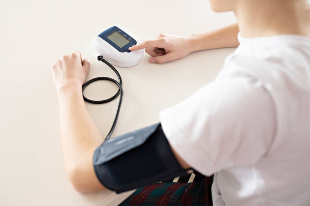 Hypertension concept. Teenager is measuring blood pressure with  - Photo, Image