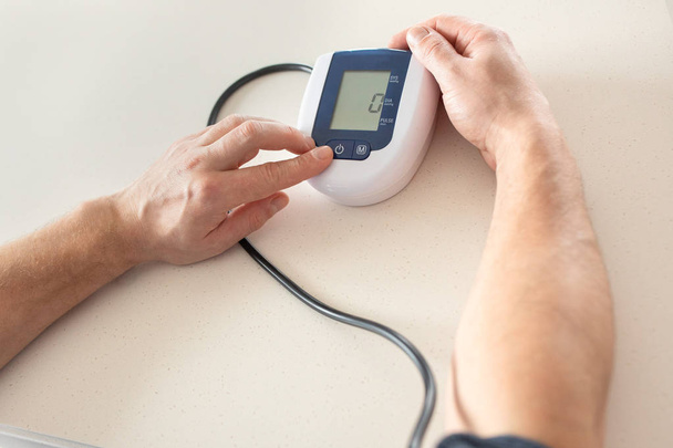 Концепция гипертонии. Мужчина измеряет кровяное давление с помощью монитора
 - Фото, изображение