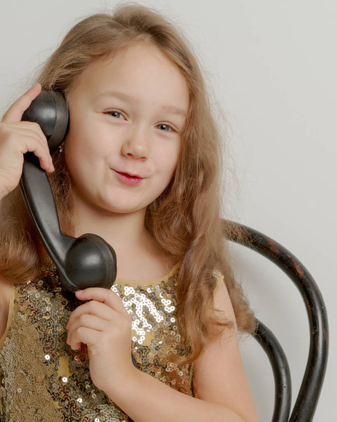 A little girl is ringing on the old phone. - Φωτογραφία, εικόνα