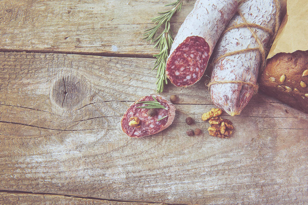 Italian salami wih sea salt, rosemary, garlic and nuts on paper. Rustic style. Close up. - Фото, зображення