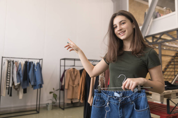 The girl in the store chooses his jeans, finds out where the dressing room - Foto, afbeelding